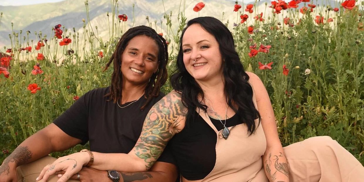 Two women smiling together in a vibrant poppy field.