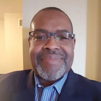 Smiling man wearing glasses and a suit jacket.