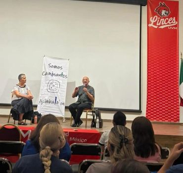 Charla en silla de ruedas frente a grupo en auditorio.