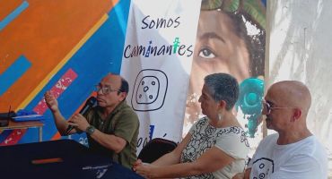 Tres personas en una charla con fondo colorido y cartel.