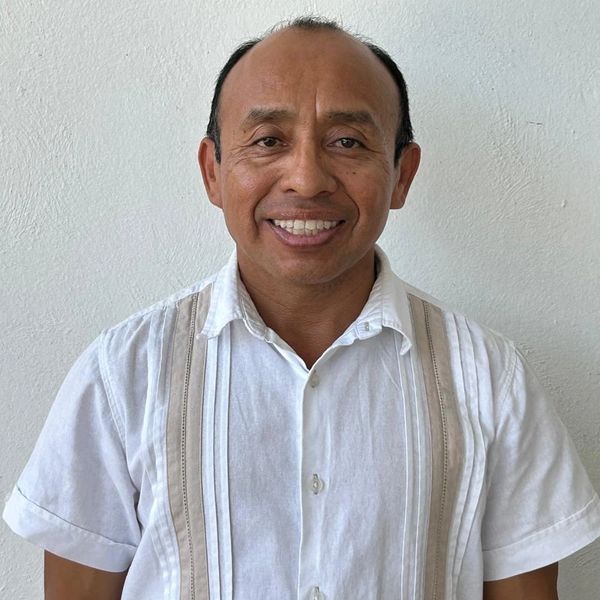Hombre sonriente con camisa blanca de manga corta.