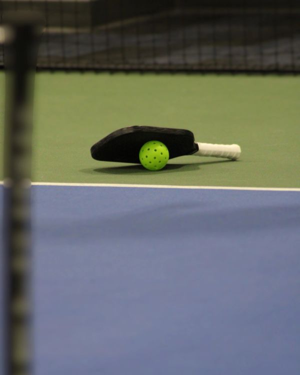 Pickleball paddle and ball on court.