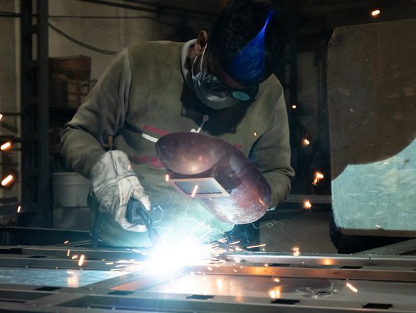 A welder in protective gear welding metal with sparks flying.