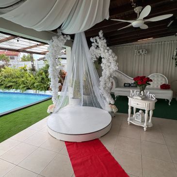Escenario de boda con decoración blanca junto a una piscina.