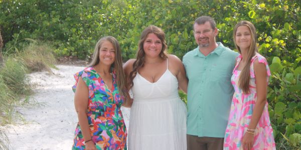 Family posing happily on a sandy path with greenery.