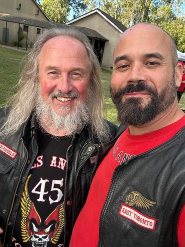 Two men wearing leather jackets with club patches.