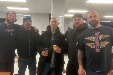 Five men posing indoors, some holding food and drinks.