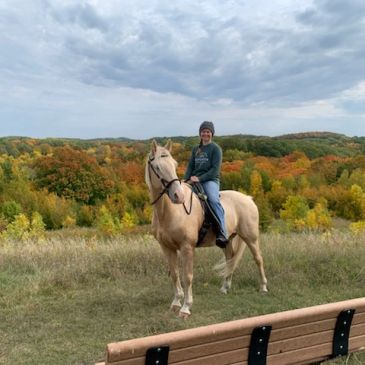 Person riding horse in a scenic fall landscape.