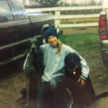 Person with two large dogs outside between cars.
