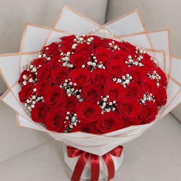 A beautiful bouquet of red roses with white baby's breath wrapped elegantly.