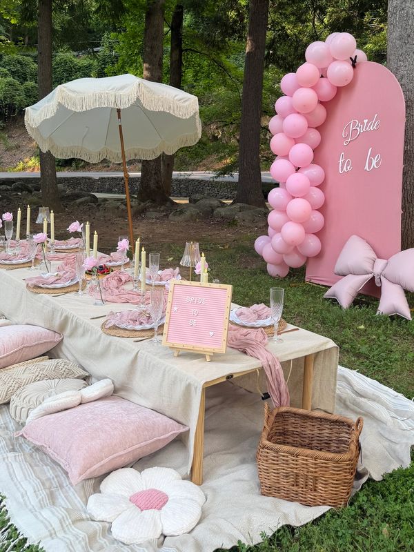 Outdoor bridal shower setup with pink decorations and table settings.