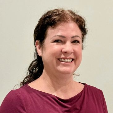 Smiling woman with curly dark hair in a burgundy top.
