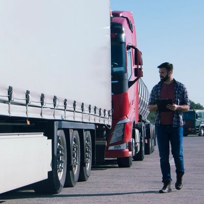 Man inspecting trucks in a parking lot with a clipboard.