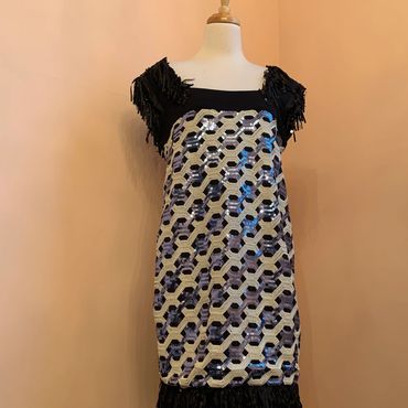 Sleeveless dress with geometric pattern and fringe details on shoulders and hem.