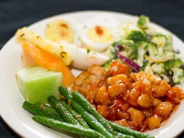 A plate with chickpeas, green beans, boiled egg, salad, and melon.