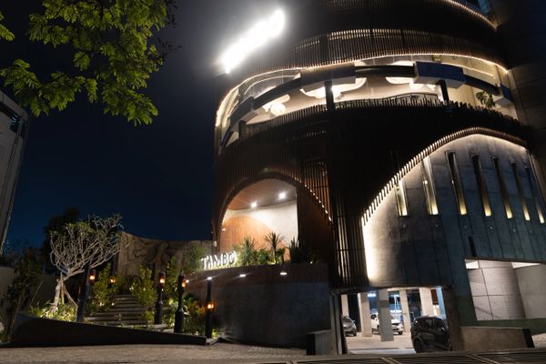 Modern building entrance illuminated at night with surrounding greenery.