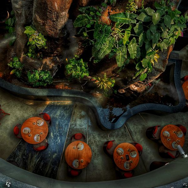 Top view of a cozy outdoor dining area with round wooden tables and red chairs near lush greenery.