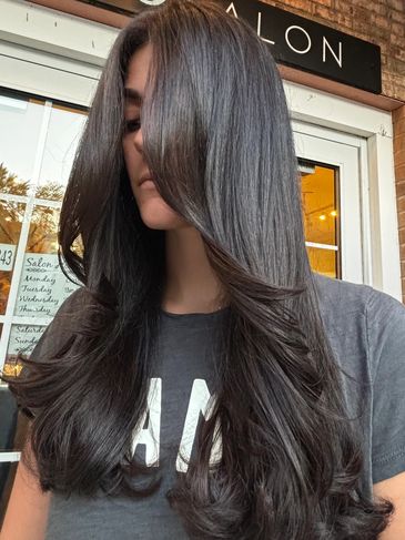 Woman with long, shiny black hair styled in soft waves.