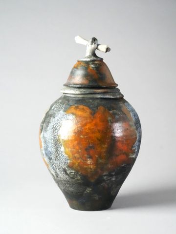 Handcrafted ceramic jar with an artistic lid handle and a rustic, earthy glaze.