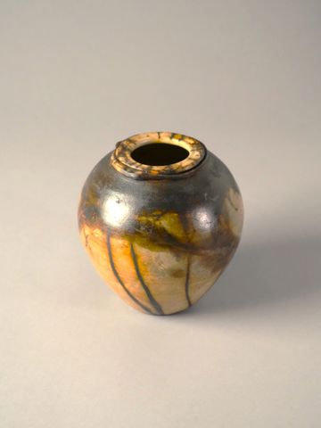 Small round ceramic vase with earthy tones and a narrow opening.