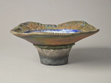 Rustic ceramic bowl with textured, cracked glaze and earthy tones.