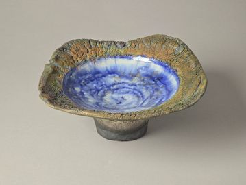 Unique ceramic bowl with a textured earthy rim and glossy blue interior.