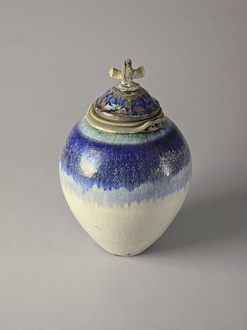 Ceramic jar with blue glaze and a unique lid design.