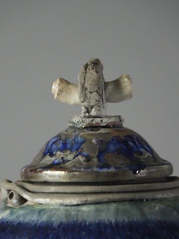 Close-up of a ceramic lid with a unique textured knob and blue glaze.