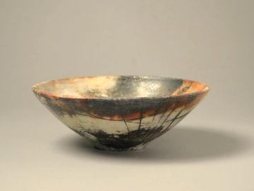 A rustic ceramic bowl with black and reddish patterns.