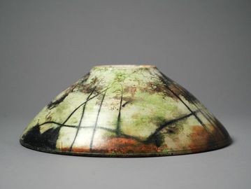 Artistic ceramic bowl with abstract green, black, and brown designs.