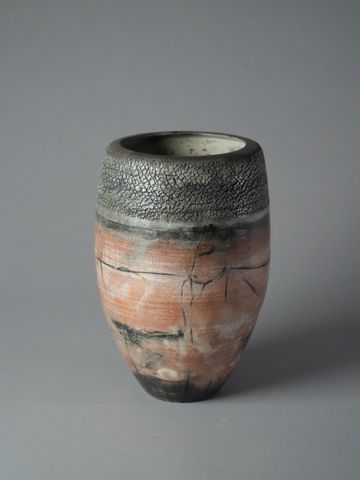 Rustic ceramic vase with textured black and orange glaze.