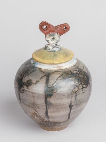 A round ceramic jar with a yellow lid and a red heart-shaped handle.