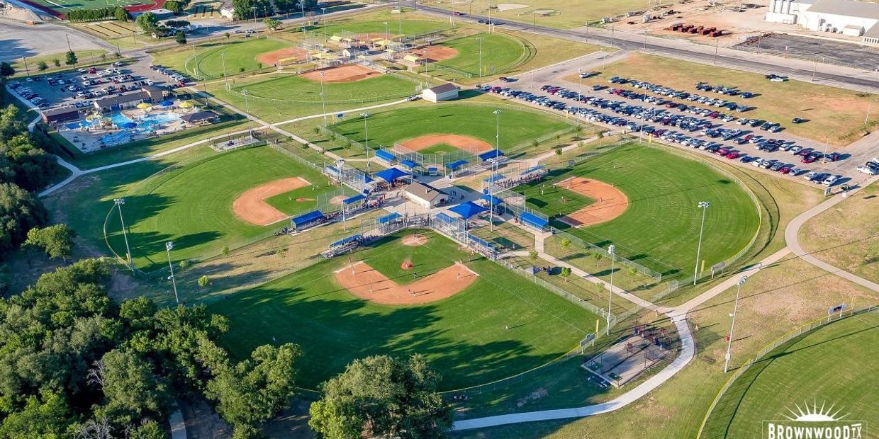 Aerial view of a baseball complex with multiple fields and parking area.