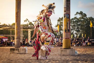 A Native American dancer in traditional regalia performing at a cultural event.