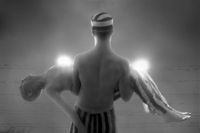 Man in striped swimwear holding two unconscious people with glowing heads.