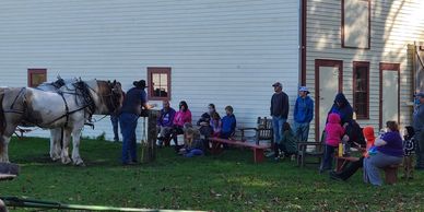 John talks to a group about historic modes of travel with draft horses waiting to go for a wagon ride.
