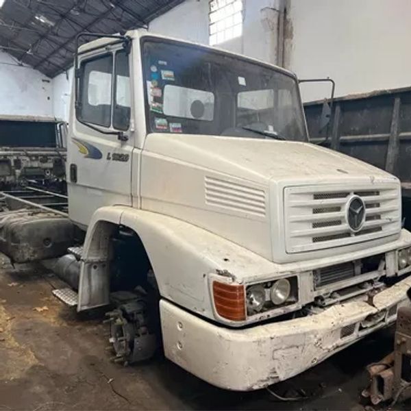 Old white truck without wheels in a garage.