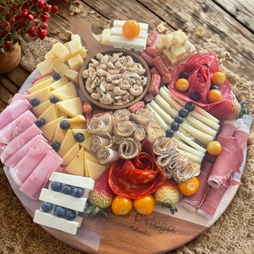 A colorful charcuterie board with cheeses, meats, nuts, and fruits.