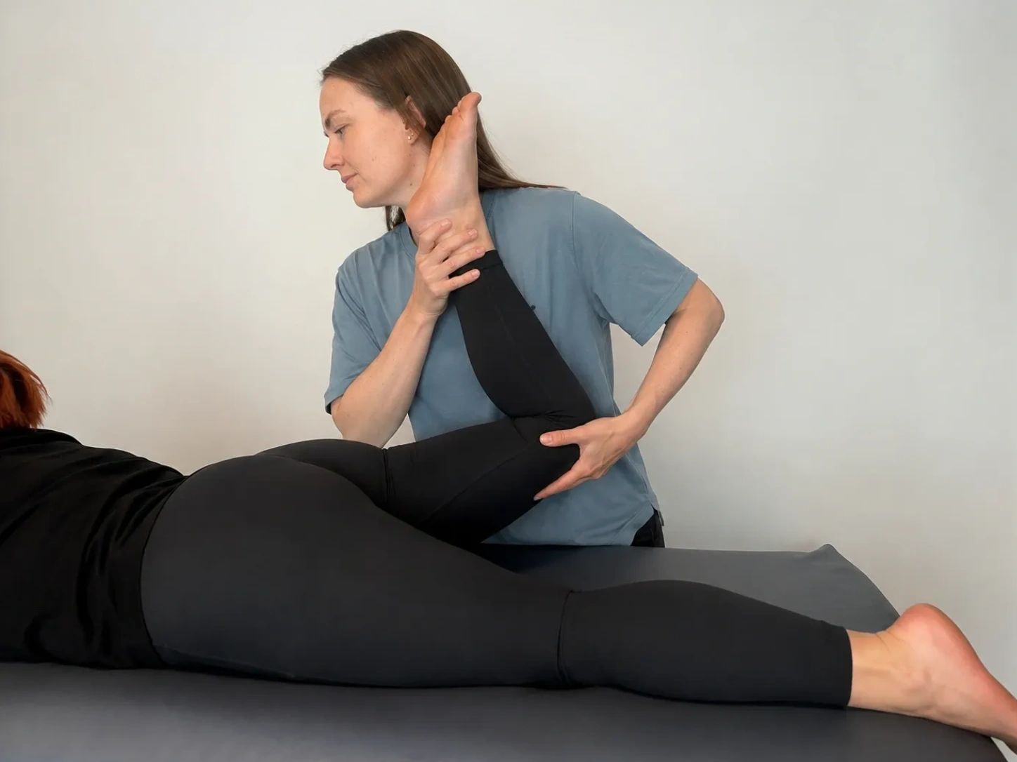 A therapist stretches a patient's leg during a physical therapy session.