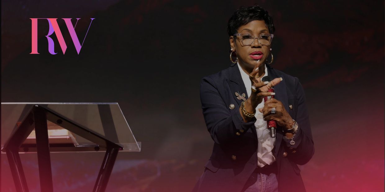 Woman speaking passionately on stage with microphone and glasses.