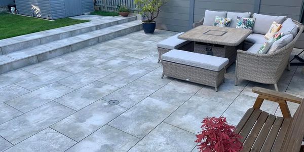 Porcelain slabbing with two steps to grassed garden and a composite fence