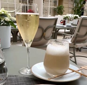 a glass of bubbly champagne and a latte sit on a table in the hotel's atrium restaurant.
