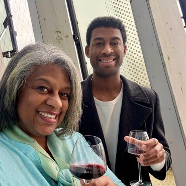 Greer and Donovan holding glasses of red wine, on the rooftop of La Cité du Vin, Bordeaux’s wine mus