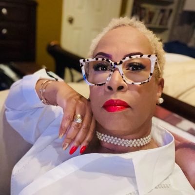Confident woman with bold glasses, red lipstick, and pearl necklace.