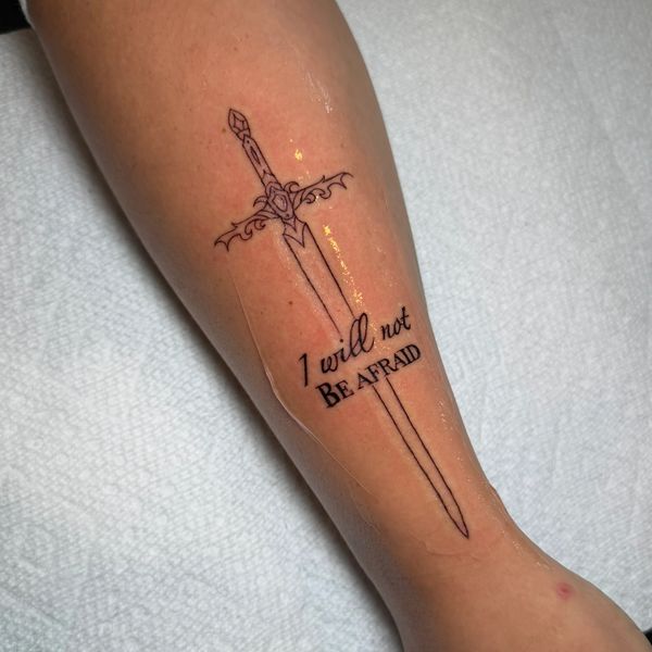 Tattoo of a sword with the phrase 'I will not be afraid' on a forearm.