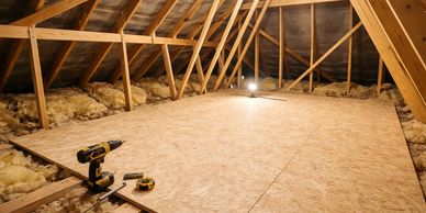 Insulated attic with wooden flooring and construction tools.