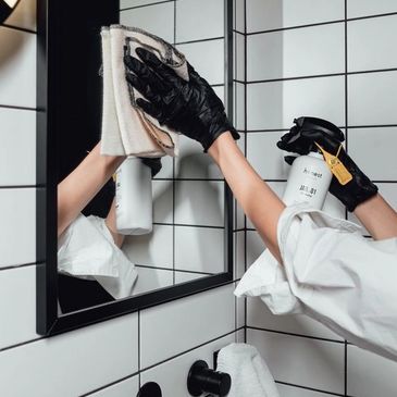 Woman wiping bathroom mirror