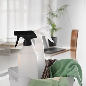 White basket with green cleaning gloves and cleaning products