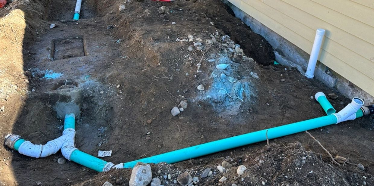 Exposed PVC drain and septic line under repair next to residential foundation in Pierce County WA