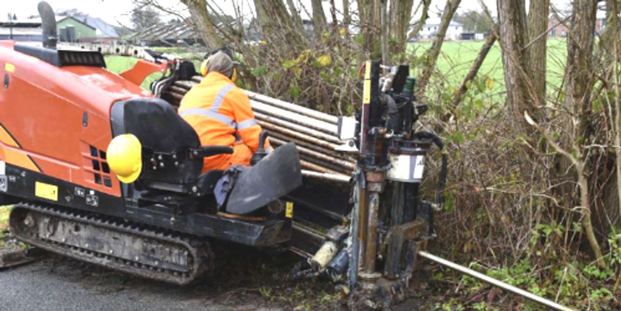 Directional boring machine installing new trenchless waterline under yard without open excavation